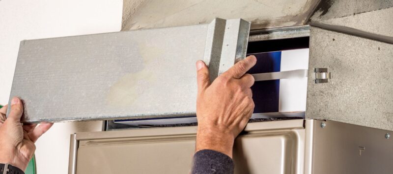 Technician adjusting the panel of a furnace for HVAC maintenance