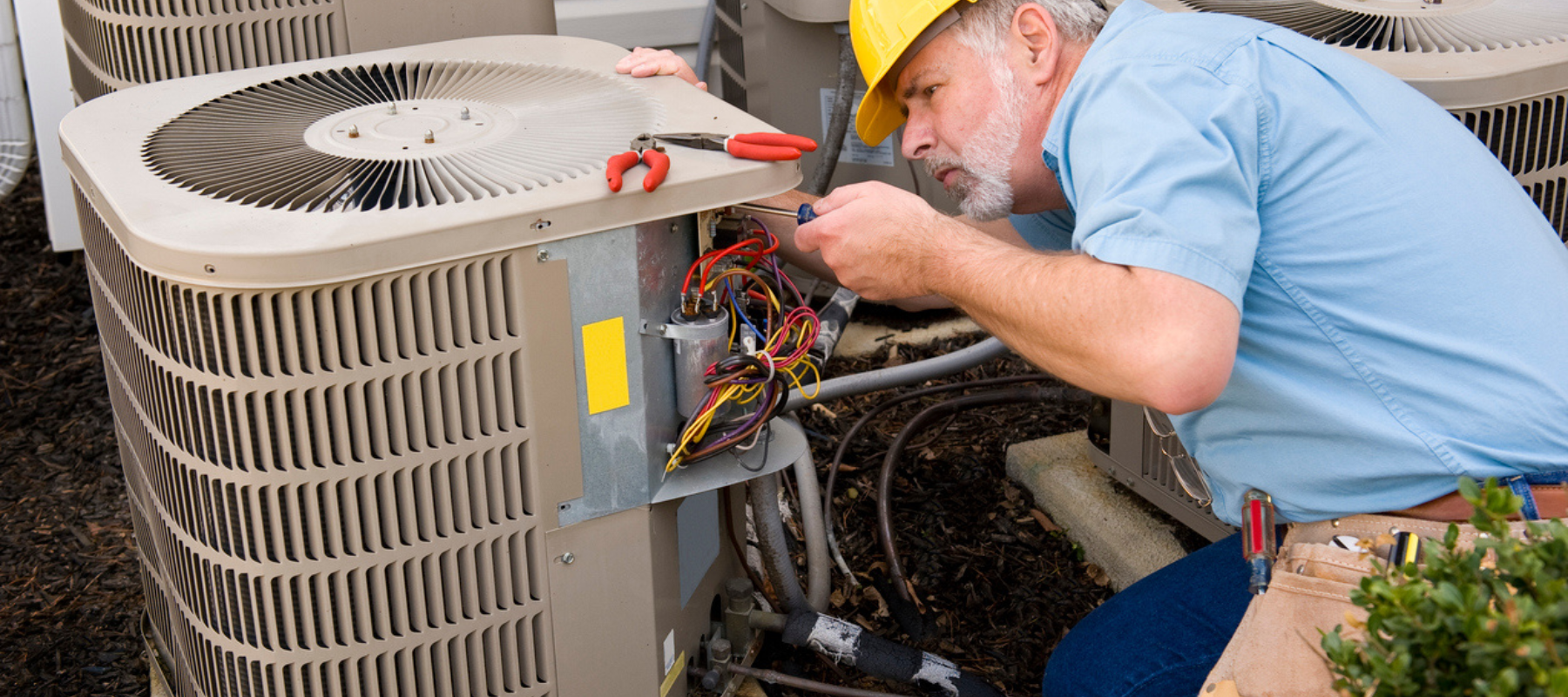 hvac technician performing maintenance on an outdoor hvac unit