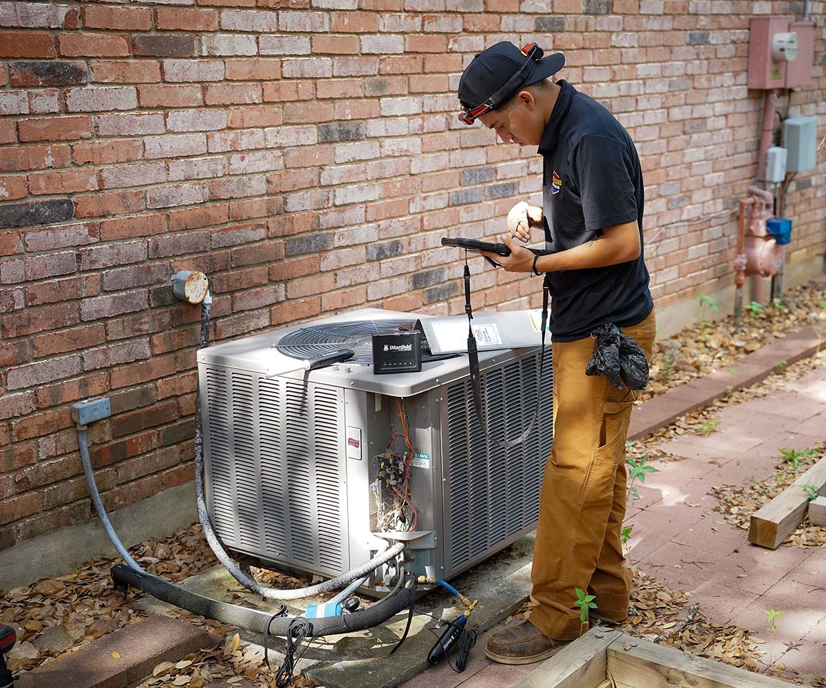 Honeycomb HVAC technician using a tablet after installing condenser