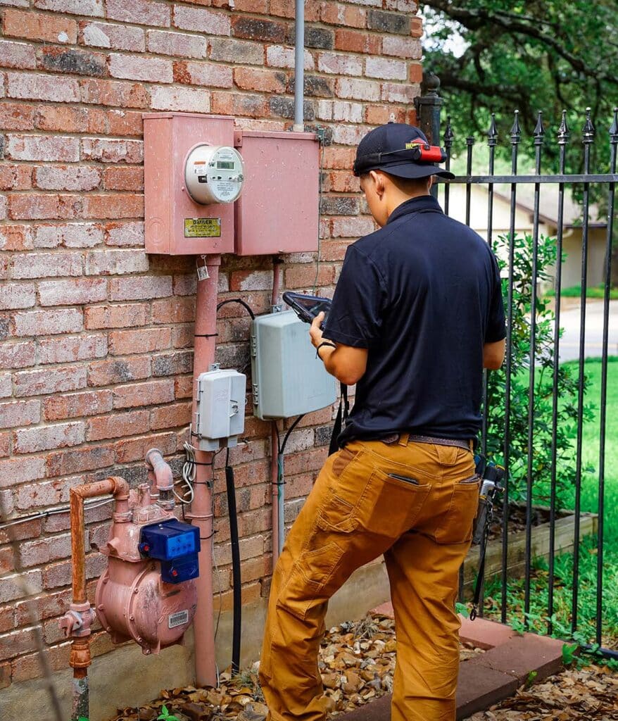 Technician inspecting a utility meter on a brick wall
