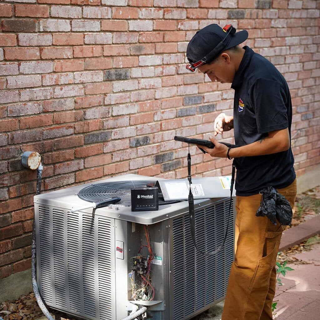 Honeycomb HVAC technician using a tablet after installing condenser
