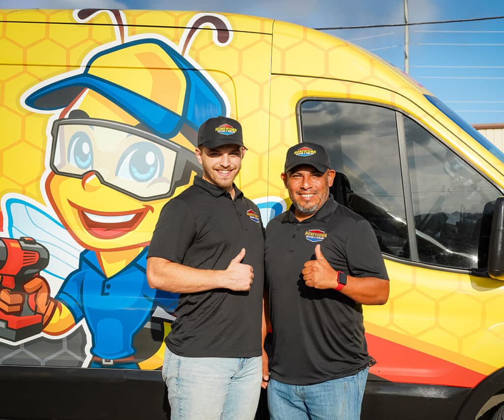 Two team members smiling and posing in front of Honeycomb van