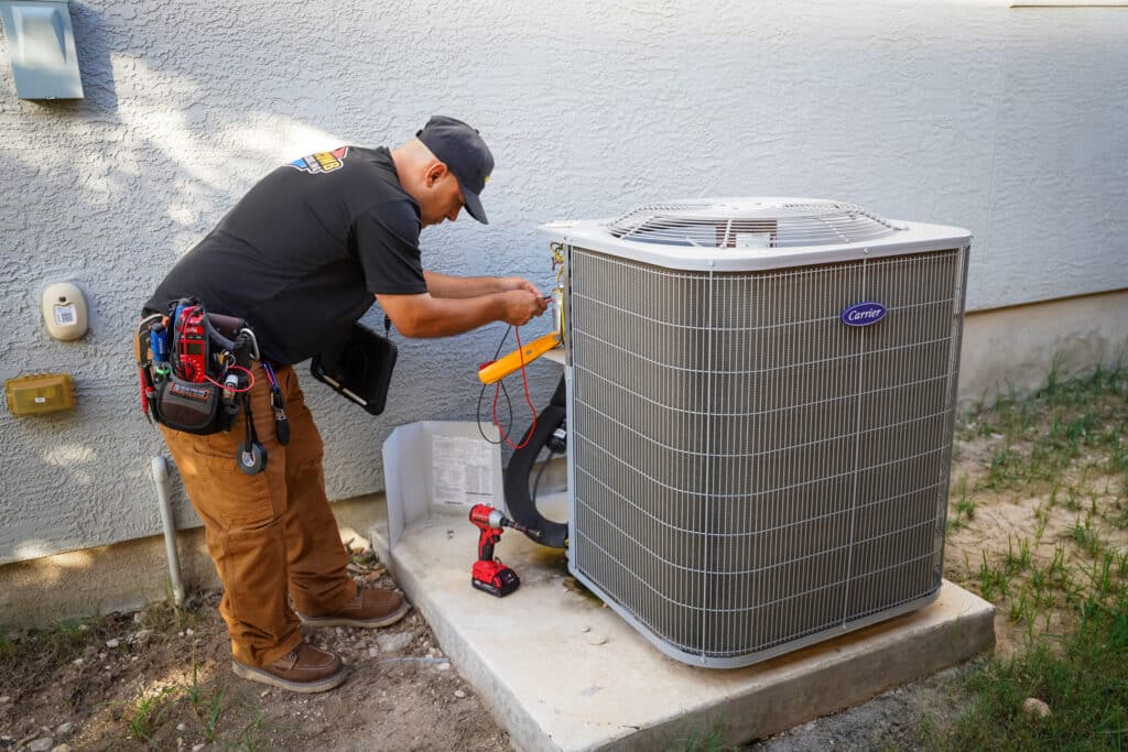 HVAC technician testing a heat pump capacitor in Bulverde, TX to prevent electrical failure caused by extreme Hill Country heat and caliche dust buildup. Heat Pumps Services in Bulverde