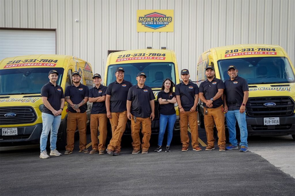The professional technician team of Honeycomb Heating & Cooling standing in front of their yellow service vans, showcasing the group dedicated to providing the best AC in San Antonio.