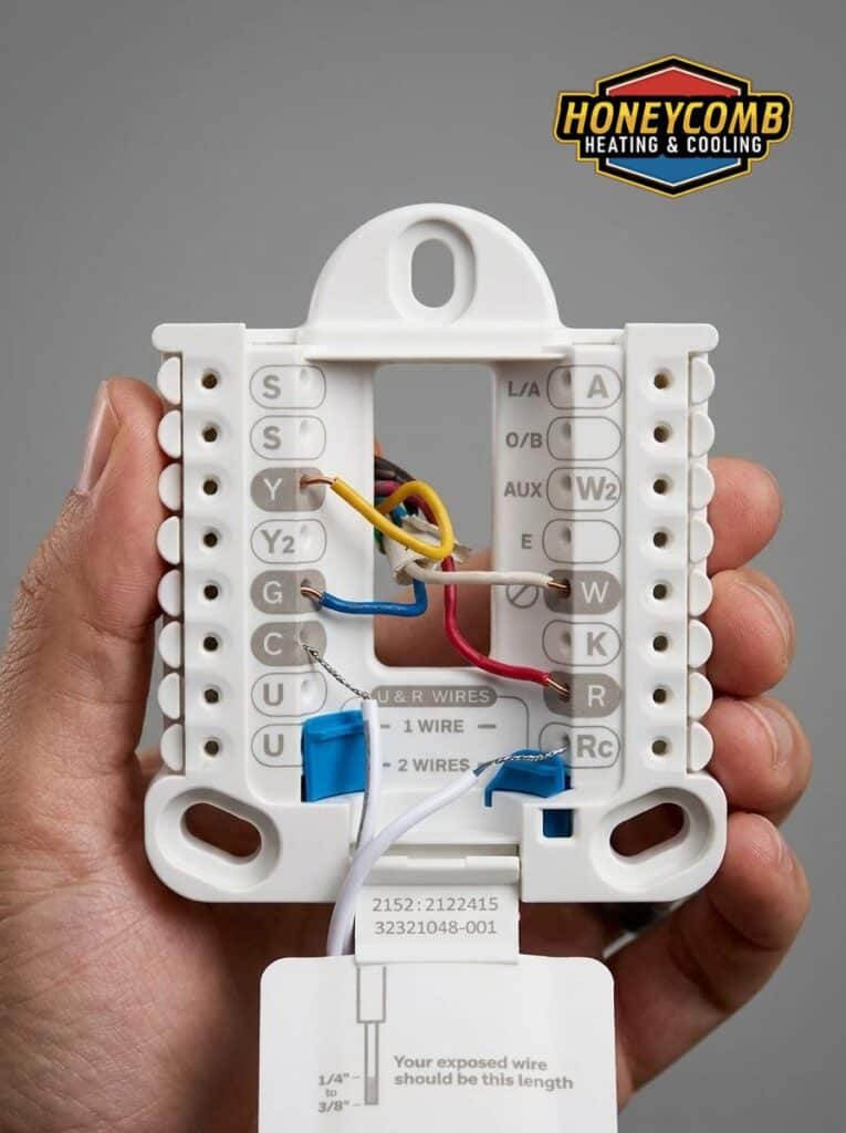 A close-up view of an HVAC baseplate wiring terminal being handled during troubleshooting, illustrating common loose or improper wire connections that lead to a thermostat not working.