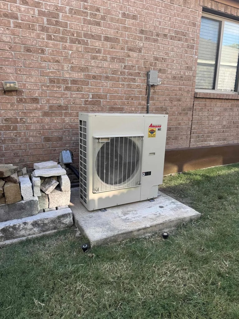 High-Efficiency Inverter Unit Installation: Two-Stage vs Inverter AC San Antonio | Honeycomb Exterior view of a slim profile Amana inverter unit on a concrete pad, demonstrating space-saving benefits in two-stage vs inverter ac San Antonio, by Honeycomb.