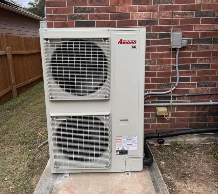 High-Capacity Variable Speed Installation: Fixing an Oversized AC San Antonio | Honeycomb Vertical dual-fan Amana side-discharge AC condenser unit installed on a concrete pad, solving high humidity and short-cycling caused by an oversized AC San Antonio, by Honeycomb.